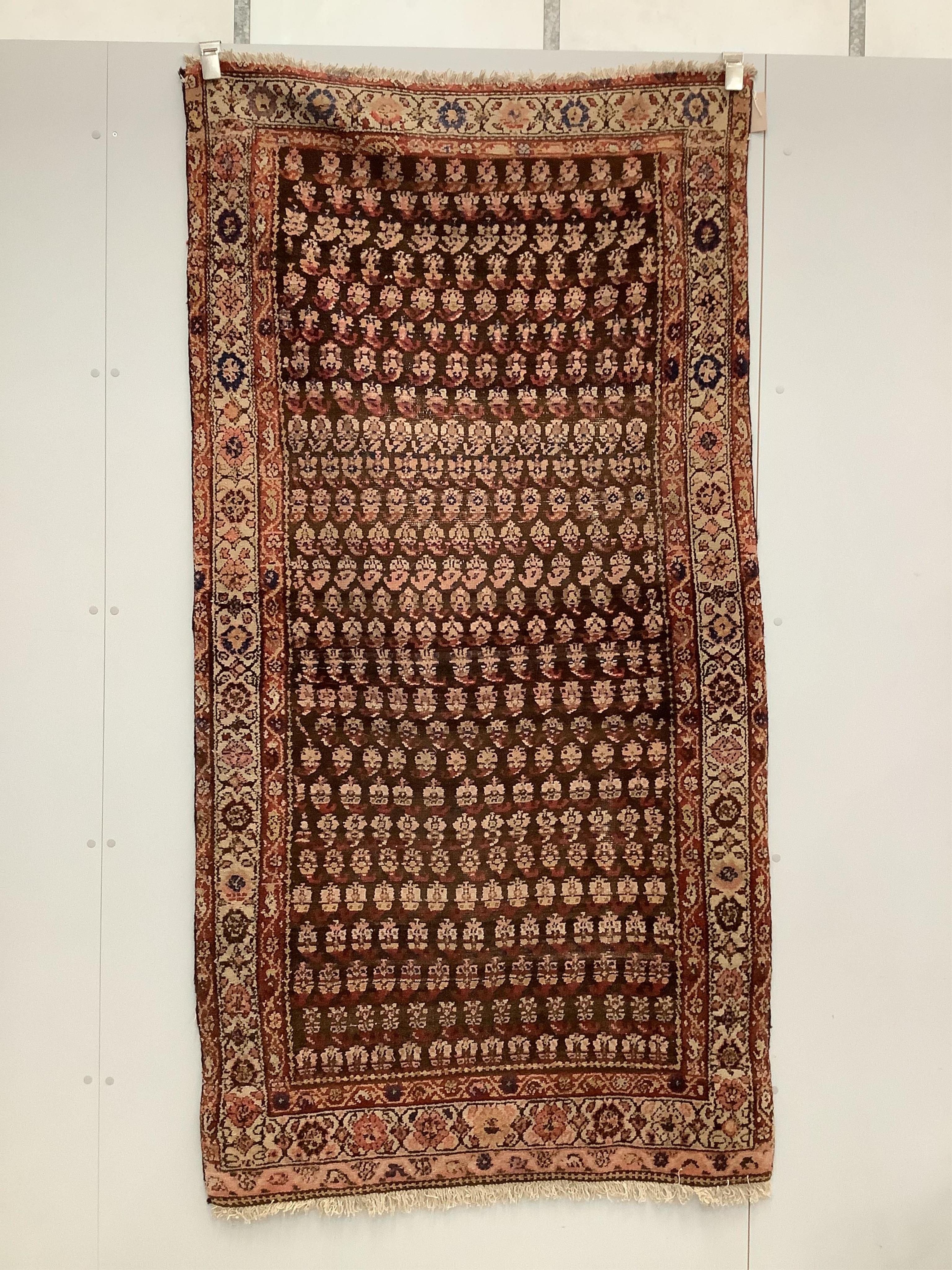 A Caucasian rug, woven with rows of botehs on a burgundy ground, 202 x 104cm. Condition - fair